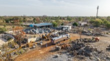 Yard operations with trucks, cranes, and sorted stone stock