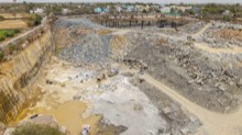 Layered quarry walls, haul road, and sandstone blocks below